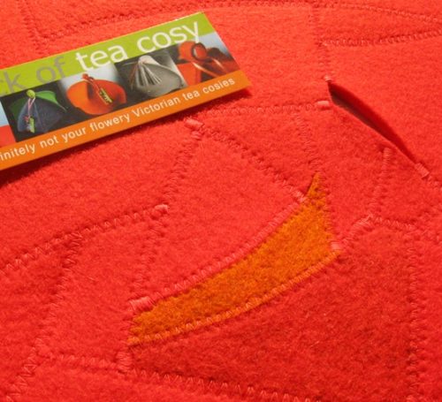 Upcycled wool felt pieces into elegant table topper in reds and oranges