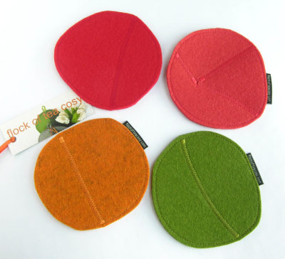 Four thick wool felt cup coasters in red, tangerine, coral orange and moss green with zig-zag stitching upcycled from scraps.
