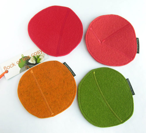Four thick wool felt cup coasters in red, tangerine, coral orange and moss green with zig-zag stitching upcycled from scraps.
