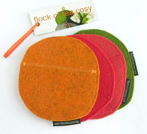 Four colourful wool felt mug coasters made from thick wool felt in tangerine, red, coral orange and moss green.