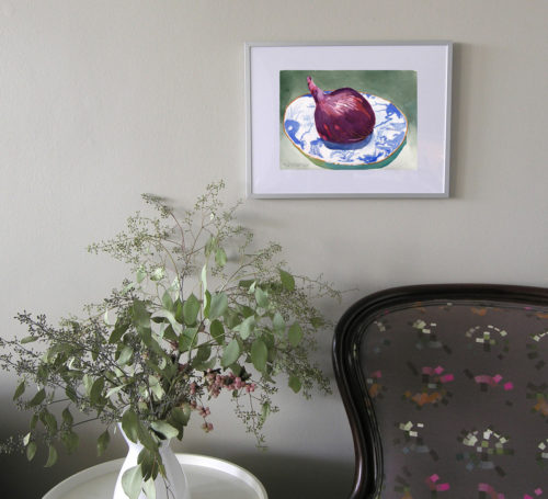 Small original watercolour by michaelle mclean of a red onion on a Blue Willow plate shown framed on wall over armchair