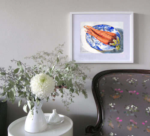 View of a white-framed painting still-life of carrots sitting on a Blue Willow-patterned plate. of