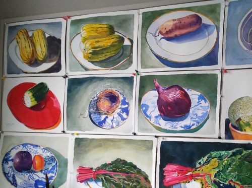 View of several small unframed very colourful watercolour paintings of vegetables and bird's nest pinned to a bulletin board.